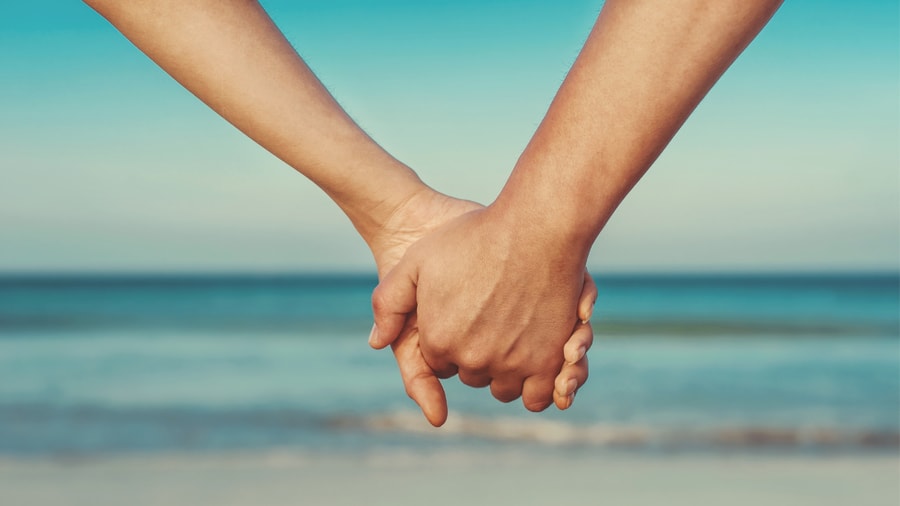 couple hold hands beach